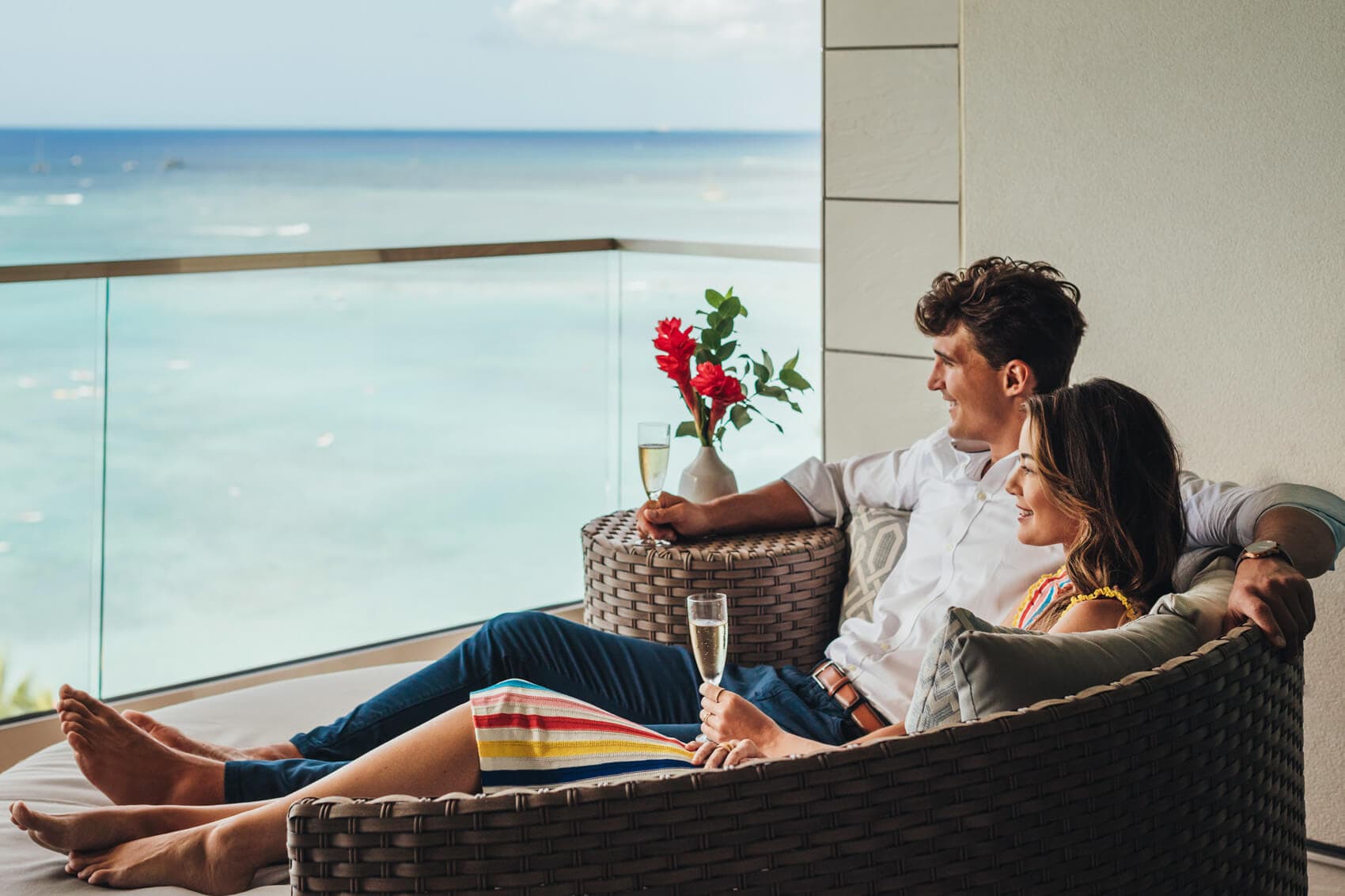 Couple enjoying wine on balcony with ocean views.