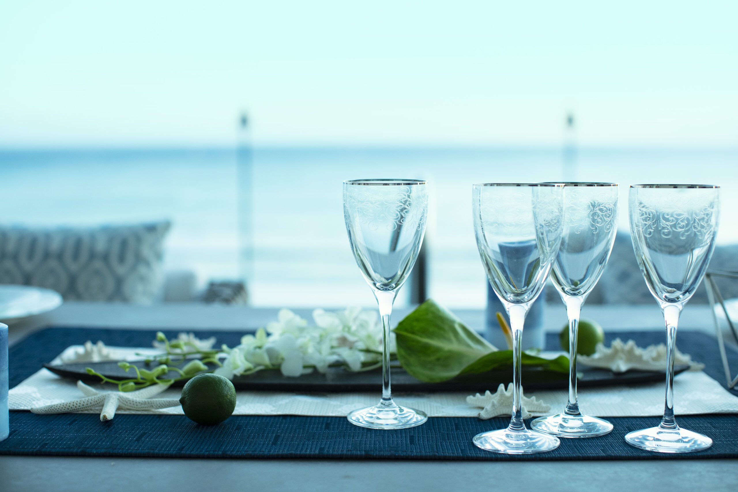 Glasses on table with view of ocean in the background.