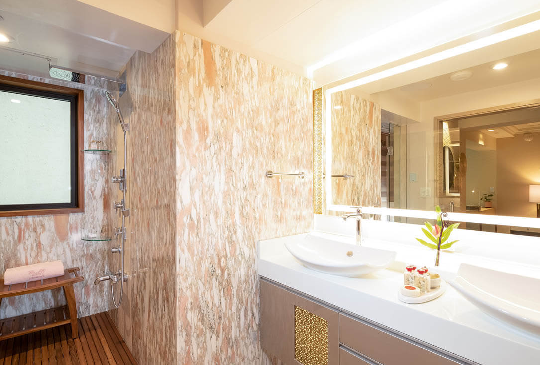 Bathroom with 2 sinks, large mirror, premium toiletries, and shower with marble walls.