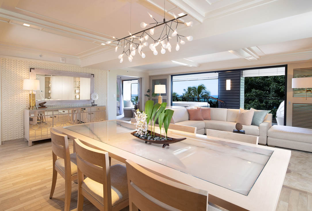 Dining area with table and chairs, opens out to living area with couch and balcony with ocean views.